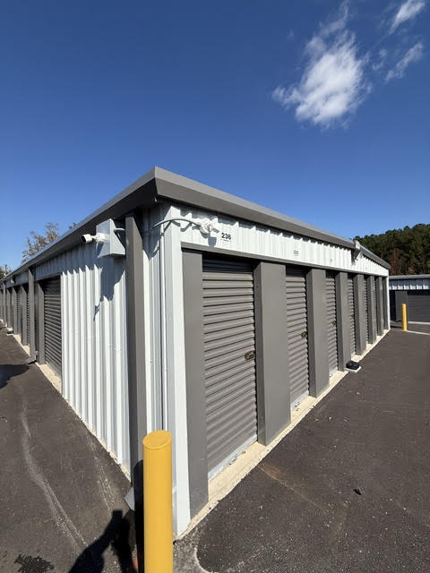 Corner of a storage building with gray roll-up doors and a security camera