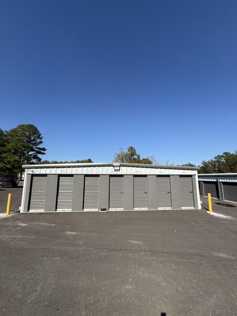 Storage building with six gray roll-up doors and yellow safety posts
