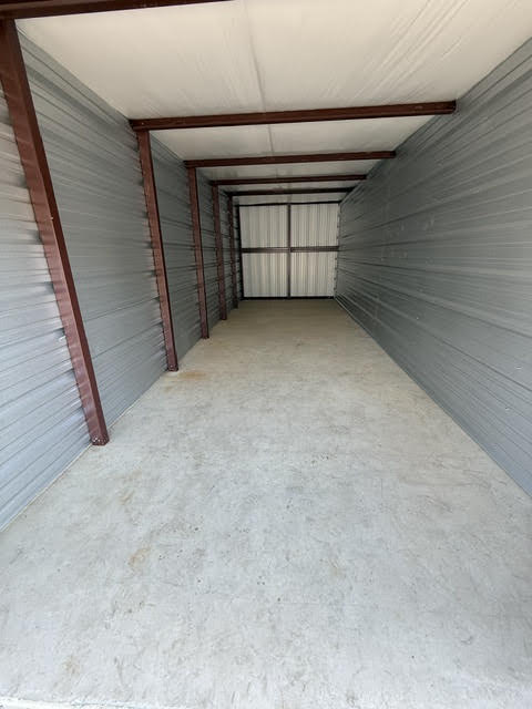 Inside a long, empty storage unit with steel walls and a concrete floor