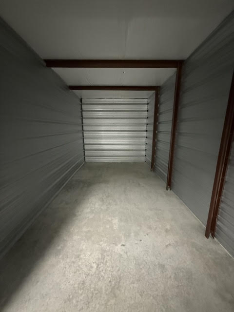 Inside an empty indoor storage unit with steel walls and a concrete floor