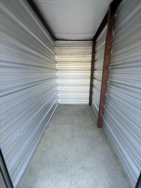 Inside a narrow, empty storage unit with steel walls