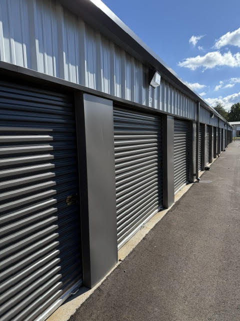Row of charcoal roll-up storage doors along a paved drive