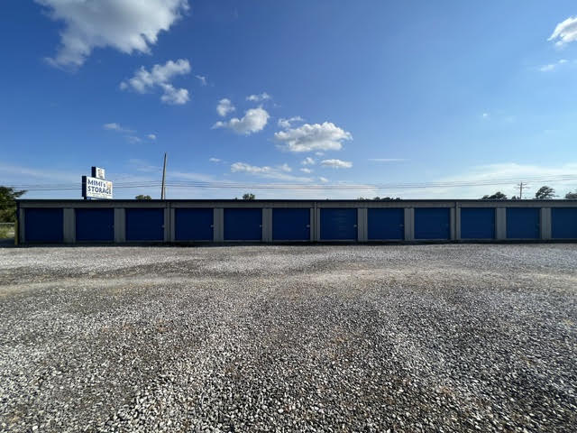 Long row of navy drive-up storage doors with the Mimi’s Storage sign in the distance
