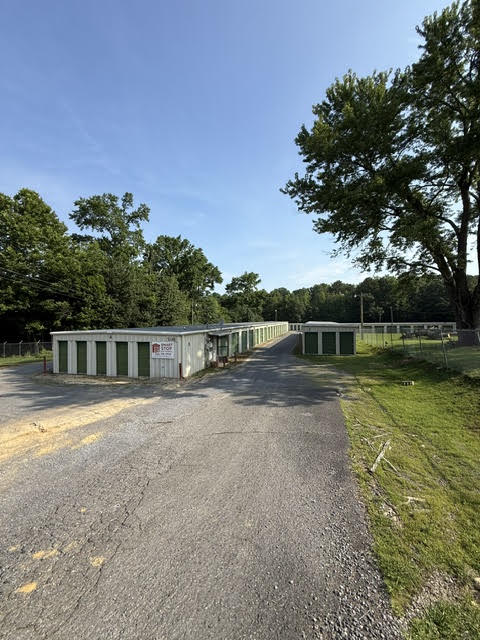 Paved driveway leading between rows of drive-up storage buildings