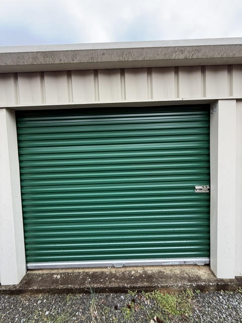 Closed green roll-up door on a drive-up storage unit